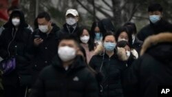 Commuters wearing face masks walk along a street in the central business district in Beijing, Jan. 12, 2023. 