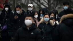 Commuters wearing face masks walk along a street in the central business district in Beijing, Jan. 12, 2023.