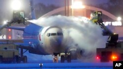 An American Airlines plane is deiced as high winds whip around 19 centimeters of new snow at Minneapolis-St. Paul International Airport, Dec. 22, 2022.