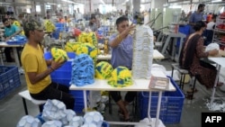 FILE - Factory workers prepare to stitch soccer balls at a manufacturing unit in Jalandhar in India's Punjab state on Aug. 22, 2022.