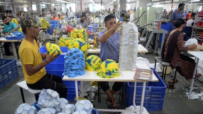 FILE - Factory workers prepare to stitch soccer balls at a manufacturing unit in Jalandhar in India's Punjab state on Aug. 22, 2022.