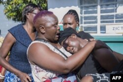 Florence Nyirenda (R) mother of Zambian student Lemekhani Nyireda, who died in the conflict in Ukraine last September, is consoled by relatives as his coffin arrives at the Kenneth Kaunda International Airport in Lusaka on December 11, 2022.