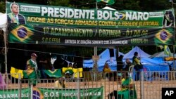 Supporters of President Jair Bolsonaro display posters reading "President Bolsonaro activates the Armed Forces against Electoral Fraud," during a protest against the October presidential election results, in front of army headquarters in Brasilia, Brazil, Dec. 21, 2022. 