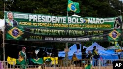 Pendukung Jair Bolsonaro membentangkan sejumlah spanduk dalam aksi protes terhadap hasil pemilu presiden di depan markas angkatan bersenjata di Brasilia, Brazil, pada 21 Desember 2022. (Foto: AP/Eraldo Peres)
