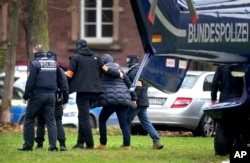 A suspect, second right, is escorted from a police helicopter in Karlsruhe, Germany, Dec. 7, 2022. Raids were carried out across much of Germany on Wednesday against suspected far-right extremists who allegedly sought to overthrow the government in an armed coup.