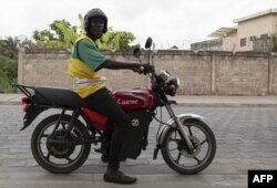 Un chauffeur de taxi moto sur sa moto électrique pose pour une photo dans les rues de Cotonou, le 21 octobre 2022.