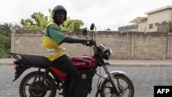 Un chauffeur de taxi moto sur sa moto électrique pose pour une photo dans les rues de Cotonou, le 21 octobre 2022.