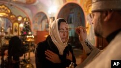 在乌克兰的康斯坦丁尼夫卡的圣诞教堂仪式中,一位东正教神职人员为一名女子行圣餐礼。(2023年1月6日)