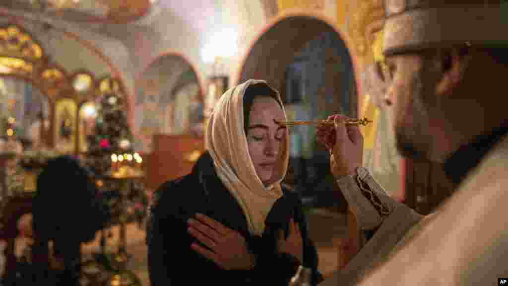 An Orthodox priest offers the holy communion to a woman during Christmas church service in Kostyantynivka, Ukraine.
