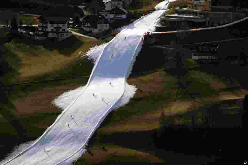 People skiing on a slope near Schladming, Austria. Sparse snowfall and unseasonably warm weather in much of Europe is allowing green grass to blanket many mountaintops across the region where snow might normally be.