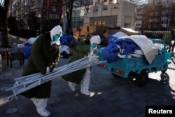 身穿防護服的大白拆除北京一個居民區的封控和檢測裝置。（2022年12月10日）