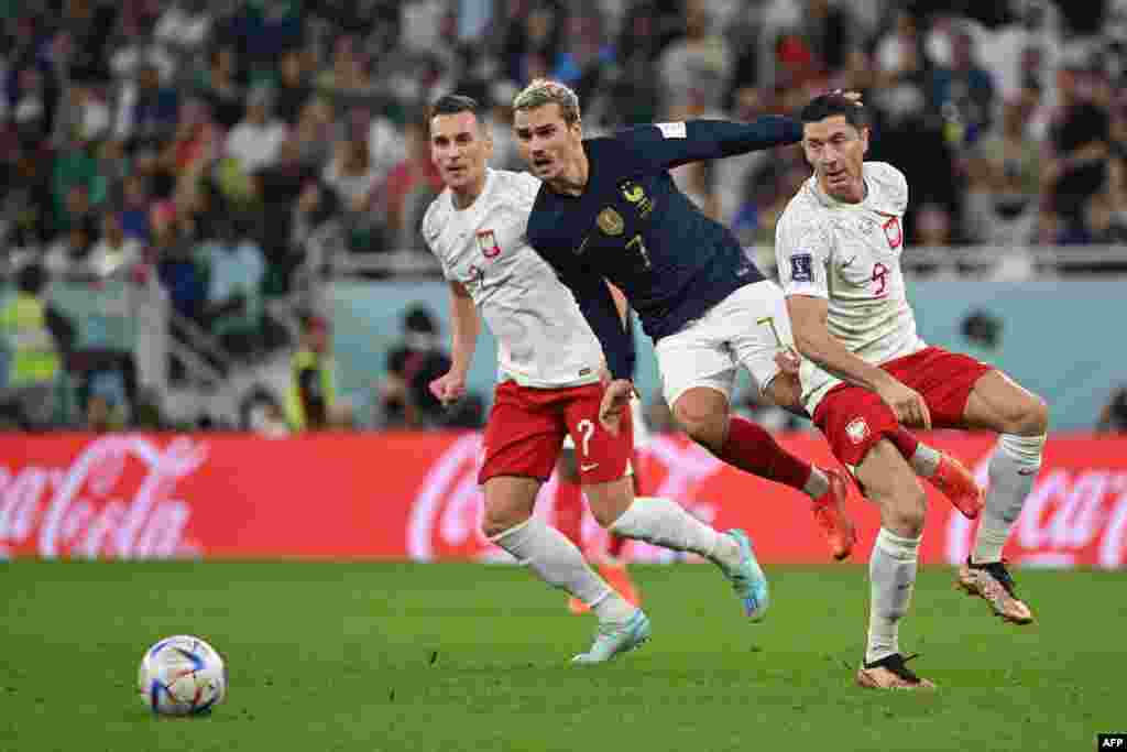 Attaquant ya France Antoine Griesmann (C) azali kowelela ndembo na attaquant ya Pologne #07 Arkdiusz Milik (G) mpe #09 Robert Lewandowski na match ya 8e ya Mondial qatar 2022 na stade Al-Thumama, Doha, 4 décembre 2022. (Photo by ANDREJ ISAKOVIC / AFP)