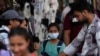 People walk past a girl wearing a face mask in a shopping district of Mumbai, India, Dec. 22, 2022.