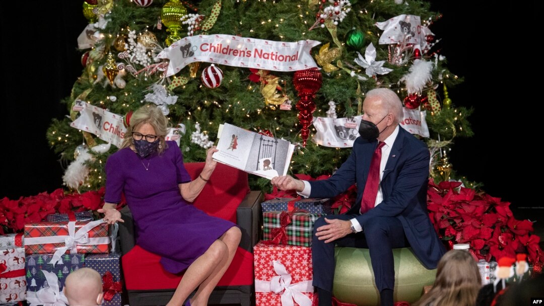 US President Joe Biden holds the book as US First Lady Jill Biden reads during a holiday visit with patients and families at Children's National Hospital in Washington, DC, on Dec. 23, 2022.