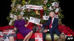 US President Joe Biden holds the book as US First Lady Jill Biden reads during a holiday visit with patients and families at Children's National Hospital in Washington, DC, on Dec. 23, 2022.