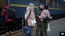 Ukrainian soldier Vasyl Khomko, 42, meets his daughter Yana and his wife Galyna, left, at the train station in Kyiv, Dec. 31, 2022. 