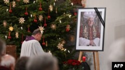 A photograph of late former Pope Emeritus Benedict XVI is seen during a Rosary prayer in the Catholic St Oswald church in his birth town Marktl am Inn, southern Germany, on Jan. 1, 2023, the day after his death. 