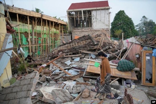 A woman walks past the ruins of buildings flattened by Monday's earthquake in Cianjur, West Java, Indonesia Tuesday, Nov. 22, 2022. The earthquake has toppled buildings on Indonesia's densely populated main island, killing a number of people and injuring hundreds. (AP Photo/Tatan Syuflana)