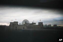 Gedung Bundestag parlemen Jerman, Gedung Reichstag difoto melalui celah tirai di kanselir di Berlin, Jerman, Rabu, 7 Desember 2022. Ribuan polisi Jerman melakukan serangkaian penggerebekan di sebagian besar Jerman terhadap tersangka ekstremis sayap kanan yang diduga berusaha menggulingkan pemerintahan melalui kudeta bersenjata. (AP/Markus Schreiber)
