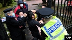 FILE - A Hong Kong protester, center, and Chinese Consulate staff scuffle as police try to intervene, in Manchester, England, Oct. 16, 2022.