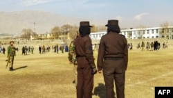 Taliban security personnel stand guard ahead of the public flogging of women and men at a football stadium in Charikar city of Parwan province, Dec. 8, 2022.