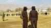 FILE - Taliban security personnel stand guard ahead of the public flogging of women and men at a football stadium in Charikar city of Parwan province, Dec. 8, 2022.
