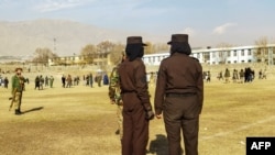 FILE - Taliban security personnel stand guard ahead of the public flogging of women and men at a football stadium in Charikar city of Parwan province, Dec. 8, 2022.