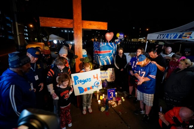 FILE - People pray during a vigil for Buffalo Bills' Damar Hamlin outside of University of Cincinnati Medical Center, in Cincinnati, Jan. 3, 2023.
