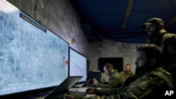 FILE - Ukrainian soldiers watch drone feeds from an underground command center in Bakhmut, Donetsk region, Ukraine, Dec. 25, 2022. 