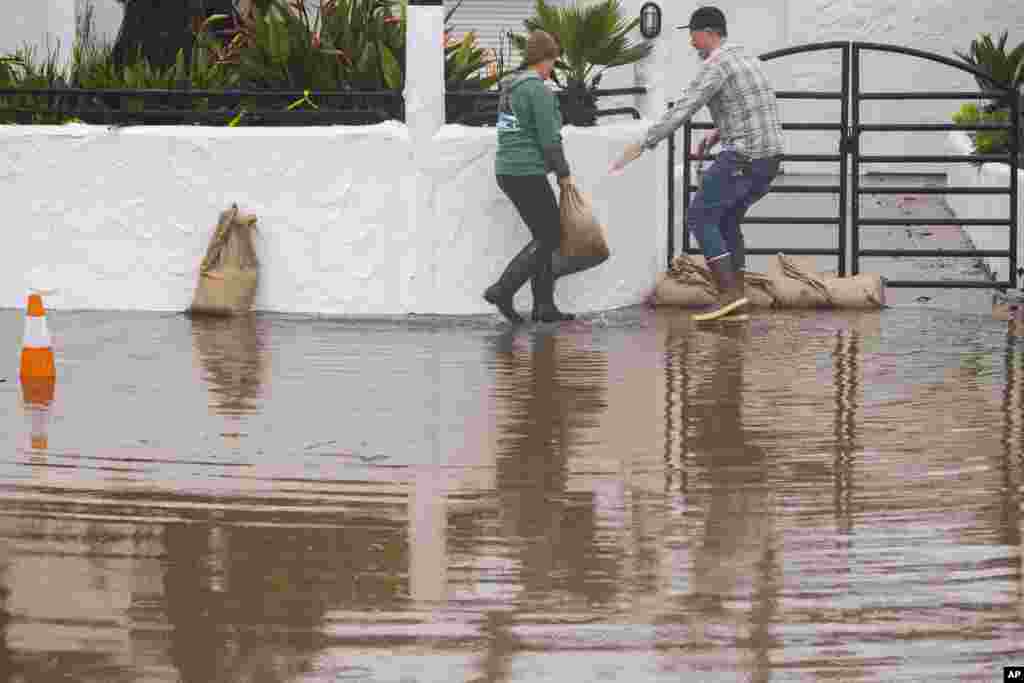 The owners of Venus Pie Trap place sandbags in front of their restaurant in the Rio Del Mar neighborhood of Aptos, Jan. 9, 2023.