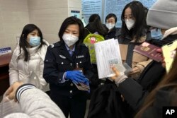Seorang petugas mengumpulkan paspor dari penduduk untuk perpanjangan dan pendaftaran ulang di kantor polisi komunitas di Beijing, Rabu, 28 Desember 2022. (AP/Ng Han Guan)