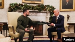 Ukraine's President Volodymyr Zelenskyy presents a soldier's medal to President Joe Biden in the Oval Office at the White House in Washington, Dec. 21, 2022.