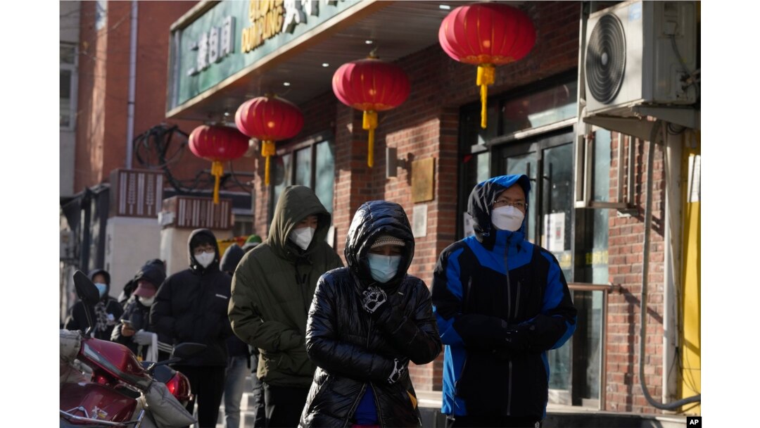 Warga mengenakan masker saat antre di tengah cuaca dingin di luar apotek untuk membeli obat sebagai persiapan menghadapi kemungkinan gelombang wabah COVID-19 di Beijing, Selasa, 13 Desember 2022. (AP/Ng Han Guan)