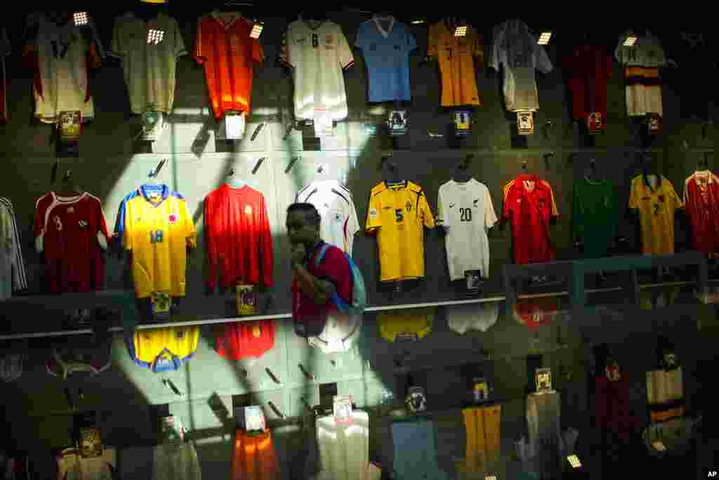 Un hombre camina frente a camisetas de equipos internacionales de fútbol exhibidas en una sala de exhibición temporal en el área de Katara en Doha.
