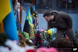 Presiden Ukraina Volodymyr Zelenskyy, memberikan penghormatan di sebuah monumen untuk pejuang Ukraina yang tewas dalam perang, di Lviv, Ukraina, 11 Januari 2023. (Foto: via AP)