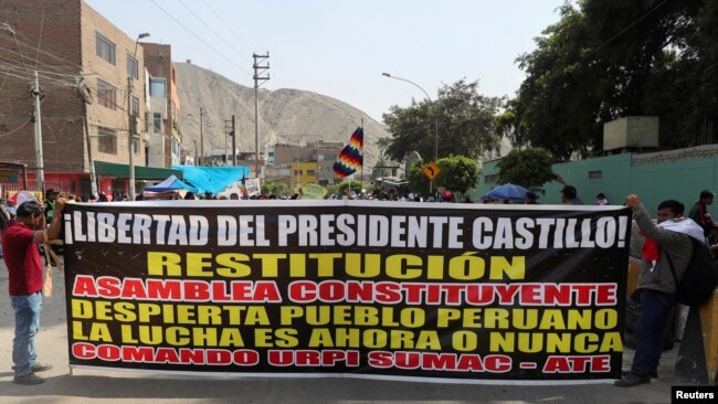 Partidarios del expresidente de Perú, Pedro Castillo, sostienen una pancarta que dice "Libertad para el presidente Castillo, Restitución, Asamblea Constituyente" mientras se reúnen frente a la prisión policial donde está detenido Castillo, en Lima, el 15 de diciembre de 2022.