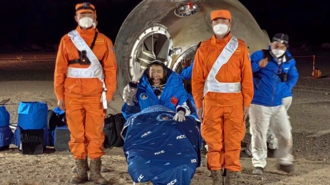 In this photo released by Xinhua News Agency, astronaut Chen Dong waves as he sits outside the re-entry capsule of the Shenzhou-14 manned space mission after it lands successfully at the Dongfeng landing site.
