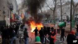 Demonstrators stand next to a burning barricade during a protest against the recent shooting at the Kurdish culture center in Paris, Saturday, Dec. 24, 2022. 