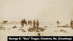 This George E. "Gus" Trager photograph shows soldiers holding moccasins and other items they have looted from the dead at the Wounded Knee Massacre site, 1890.