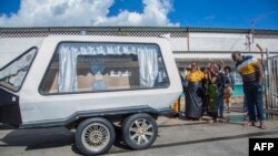 A hearse carrying the body of Zambian student Lemekhani Nyireda arrives at Kenneth Kaunda International Airport in Lusaka, Zambia, Dec. 11 2022, as relatives look on.