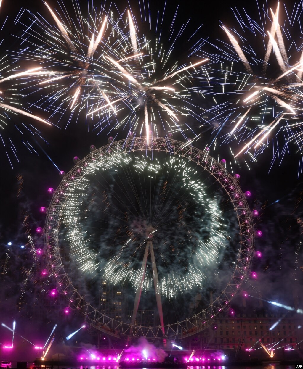 Los fuegos artificiales estallan alrededor del London Eye durante las celebraciones de Año Nuevo en el centro de Londres poco después de la medianoche del 1 de enero de 2023. [AFP]