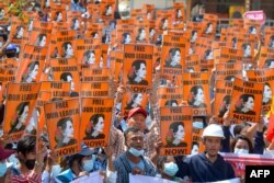 Pengunjuk rasa memegang poster dengan gambar pemimpin sipil yang ditahan Aung San Suu Kyi selama demonstrasi menentang kudeta militer di Naypyidaw, Myanmar. (Foto: AFP)