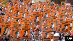 FILE - In this Feb. 28, 2021, photo protesters hold posters with the image of detained civilian leader Aung San Suu Kyi during a demonstration against the military coup in Naypyidaw, Myanmar.