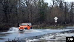Sebuah kendaraan melaju di jalan yang terendam banjir di Sebastopol, California, pada 5 Januari 2023. (Foto: AFP)