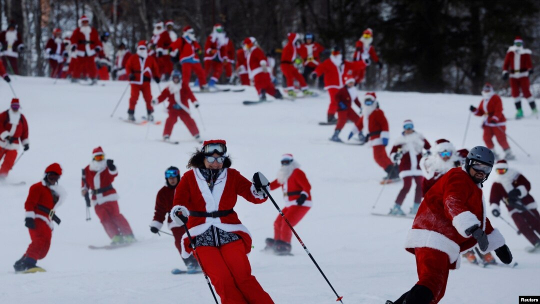 Para pemain ski berpakaian Santa berpartisipasi dalam acara amal di resor ski Sunday River di Bethel, Maine, AS, 5 Desember 2021. REUTERS/Brian Snyder