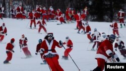 Para pemain ski berpakaian Santa berpartisipasi dalam acara amal di resor ski Sunday River di Bethel, Maine, AS, 5 Desember 2021. REUTERS/Brian Snyder