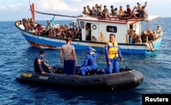 Pengungsi Rohingya yang diselamatkan nelayan terlihat di atas kapal di belakang kapal patroli di dekat pesisir Pantai Seunuddon, Aceh Utara, 24 Juni 2020. (Foto: Antara/Rahmad via REUTERS)