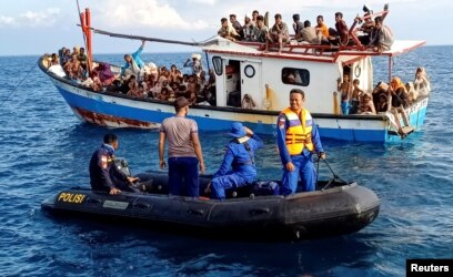 Pengungsi Rohingya yang diselamatkan nelayan terlihat di atas kapal di belakang kapal patroli di dekat pesisir Pantai Seunuddon, Aceh Utara, 24 Juni 2020. (Foto: Antara/Rahmad via REUTERS)