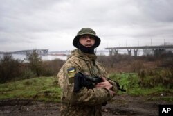 A Ukrainian serviceman patrols near the Antonovsky Bridge, which was destroyed by Russian forces after withdrawing from Kherson, Ukraine, Dec. 8, 2022.