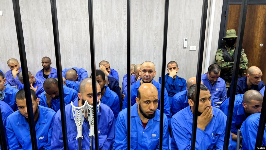 Sejumlah tersangka mantan anggota ISIS duduk di balik terali besi dalam sebuah persidangan di Misrata, Libya, pada 8 Agustus 2022. (Foto: Reuters/Ayman al-Sahili)